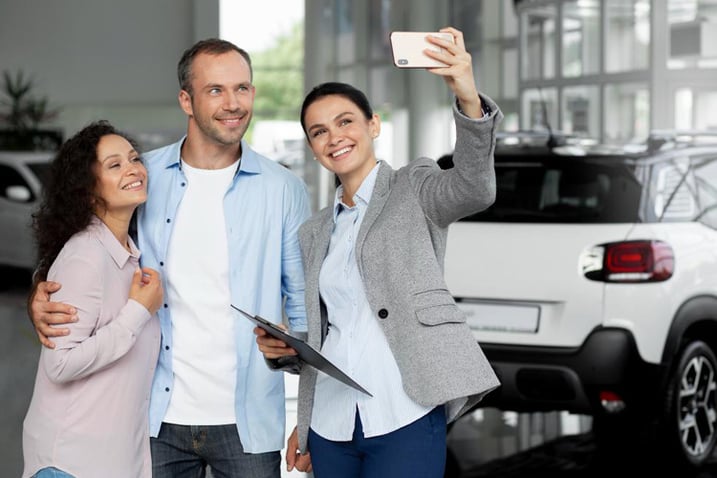 Pareja se toma foto con una vendedora de autos en un concesionario ejemplo de Marketing Digital