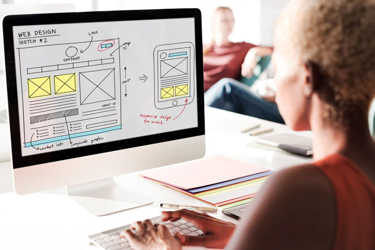 Una mujer diseñando el boceto de una página web en un computador