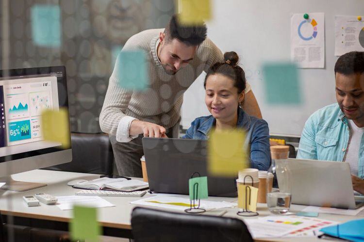 Grupo de personas en oficina trabajando alrededor de un computador